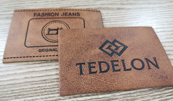 El color de encargo grabado en relieve de las parches de cuero de la PU del logotipo cose en la ropa